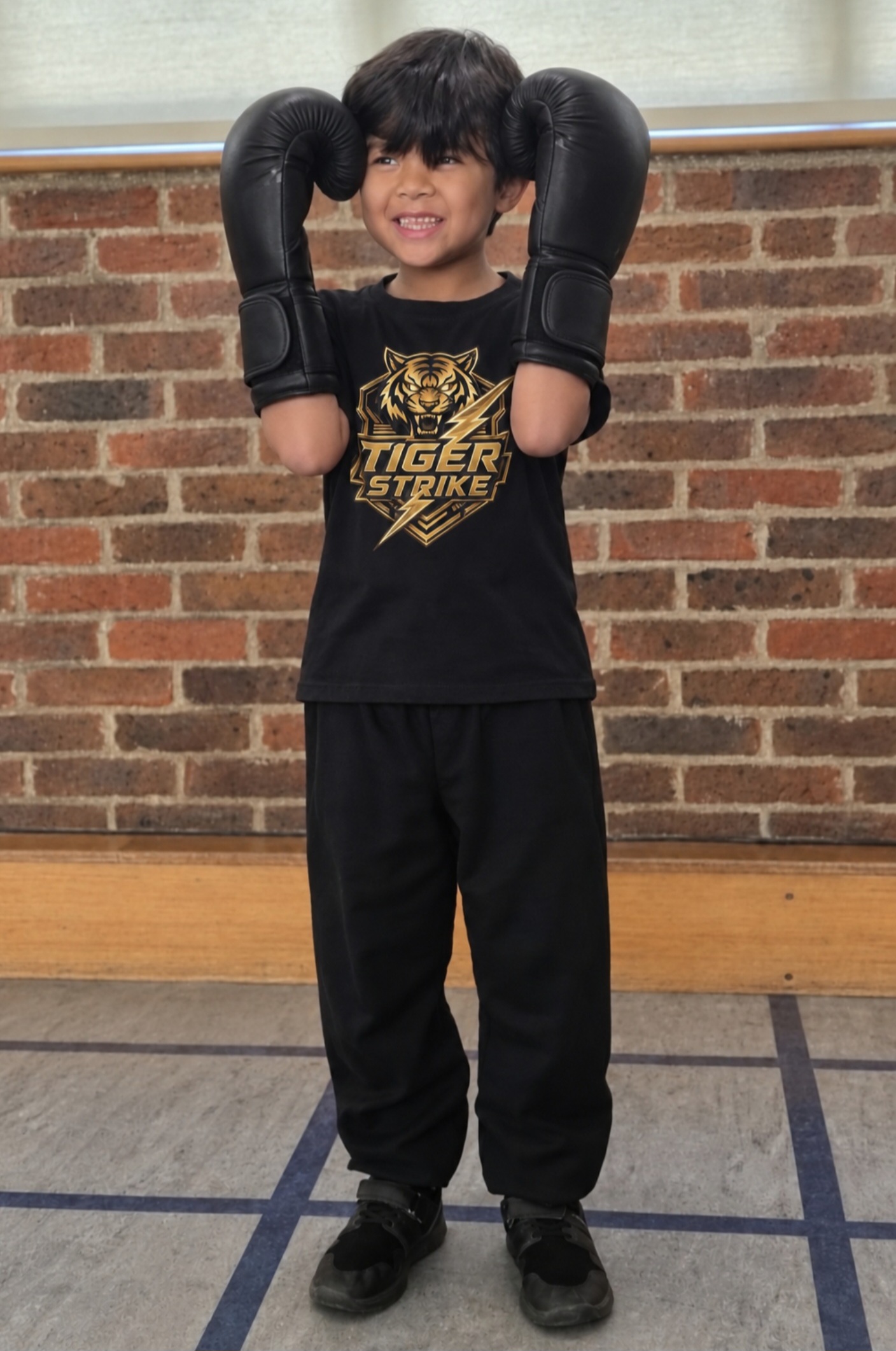 Young Tiger Strike student holding black boxing gloves by their face